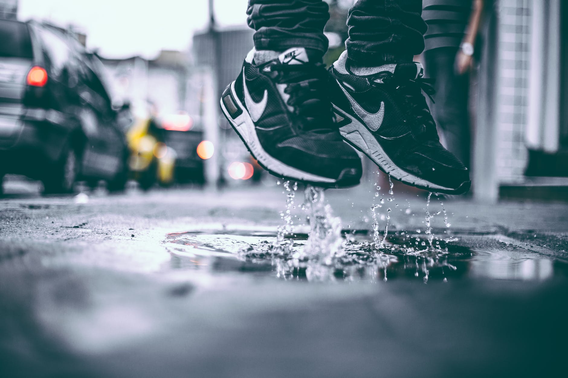 Sepasang sneakers Nike berwarna hitam melompat di atas air